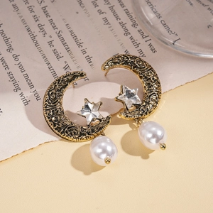 Detailed view of vintage gold crescent moon earrings with star crystal and pearl accent