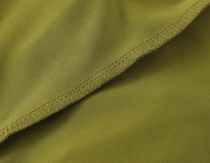 Dettaglio del tessuto dell'abito lungo verde oliva con cuciture overlock di qualità