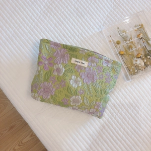 Quilted floral makeup bag with simple wish label on a white textured background
