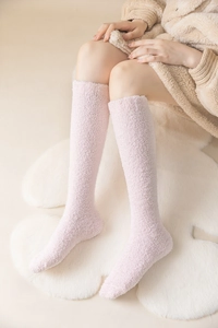 Detailed view of pink coral fleece knee-high socks worn on a cozy heart-shaped plush rug