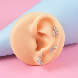 Set de 3 boucles d'oreilles en acier argenté avec zircons et motifs feuilles sur modèle