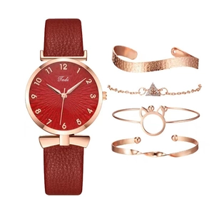 Dameshorloge van kwarts met rode leren band en vierdelige roségouden armbandset op wit decor