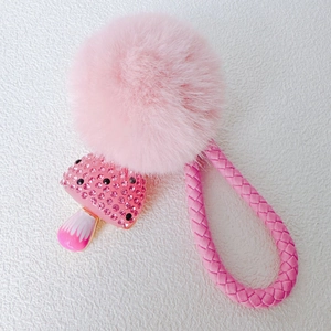 Close-up of pink fur ball and rhinestone mushroom pendant with woven rope strap