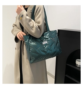 Detail of green quilted puffer tote bag showing glossy texture and fashion label