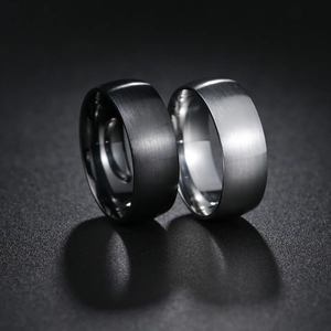 Close-up of 8mm wide brushed black and silver stainless steel rings with polished edges