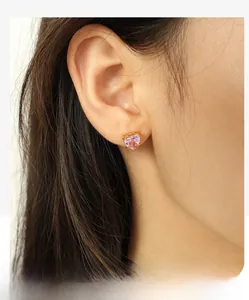 Detail of pink heart-shaped crystal earring with gold prong setting worn on female ear