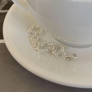 Minimalist 925 sterling silver chain bracelet with lobster clasp on ceramic saucer