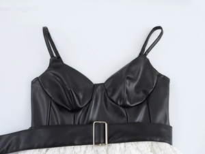 Détail du bustier en cuir PU noir avec dentelle blanche et boucle de ceinture dorée