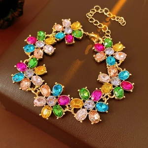 Detail of vintage gold flower bracelet with colorful gemstones on a brown leather background