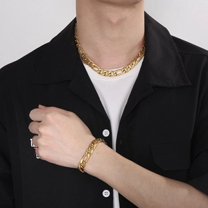 Close-up of men's gold-plated Figaro chain necklace and bracelet jewelry set on model