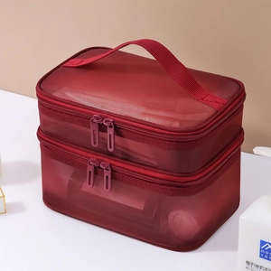 Close-up of double-layered red mesh makeup bag with handle and dual zippers on white table