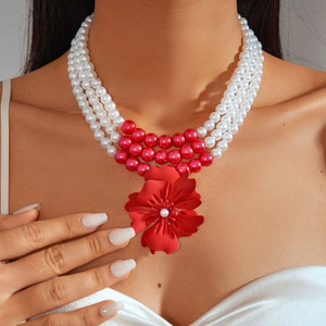 Detail of three-layer beaded pearl necklace featuring a large red 3D floral pendant