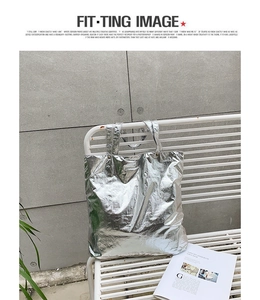 Detailed view of silver metallic tote bag with wrinkled texture on a minimalist bench