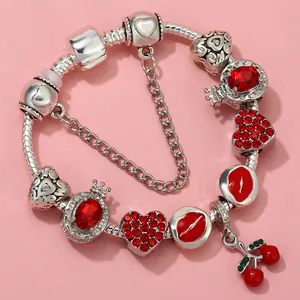 Detail of silver snake chain bracelet with red lips, crown, and cherry charms