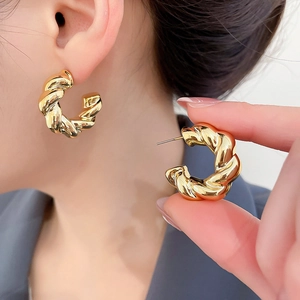 Detailed view of golden twisted hoop earrings featuring intricate rope textured metalwork