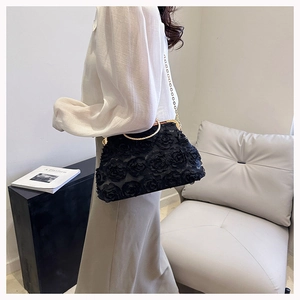 Detail of black lace 3D rose evening bag with gold circular handle and chain strap
