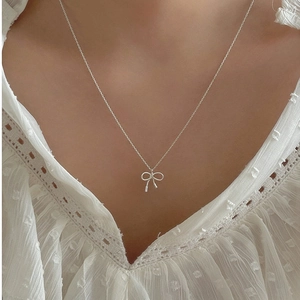 Élégant collier nœud en argent sterling 925 porté au cou sur un fond de dentelle