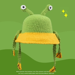 Detail of the green knit frog hat showing the cute eyes and textured wool pattern