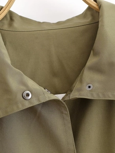 Macro view of olive green pilot jacket featuring twill texture and metallic snap buttons