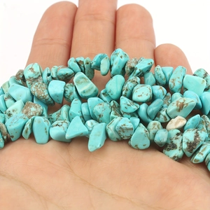 Macro shot of natural turquoise stone beads with brown textures held in palm of hand