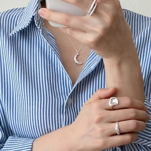 Detail of 925 sterling silver moon pendant necklace and assorted rings on a model