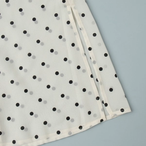 Detailed close-up of side slit and hem stitching on white polka dot chiffon fabric