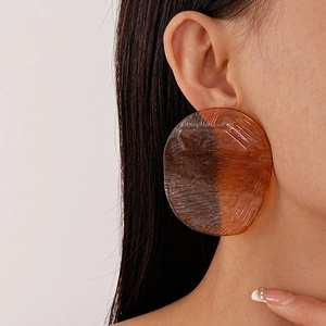 Detailed close-up of a model wearing large amber resin irregular geometric earrings