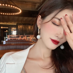 Elegant geometric gold long earrings with faux pearls and crystals on a female model