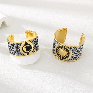 Detail view of gold sunflower and moon facial charms on leopard textured wide open bangles