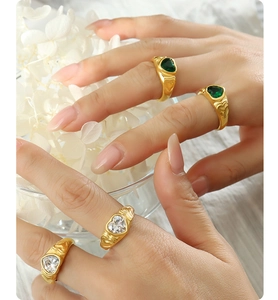 Detail of heart-shaped green and white glass stones on vintage gold-plated rings