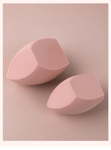 Macro shot of two soft pink makeup sponges with triple-cut edges for precise blending