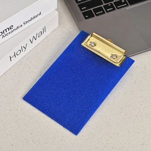 Detail shot of a blue glitter acrylic clipboard with a golden metal clip on desk