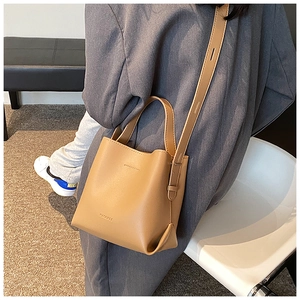 Detail view of a vintage camel bucket bag with adjustable strap and brand logo engraving