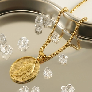Golden bead chain necklace with oval religious portrait pendant on a tray