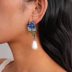 Detail of luxury flower earrings with blue rhinestones and baroque pearls worn by model