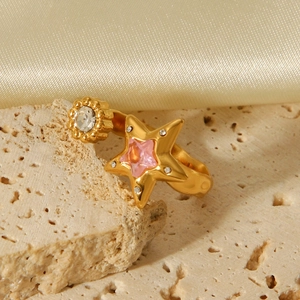 Golden star open ring with pink zircon gemstone on a warm textured stone background