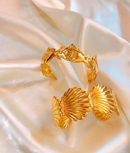 Detailed close-up of golden open bangles with fish scale and shell patterns on silk