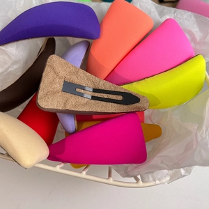 Colorful triangle sponge hair clips in various vibrant shades inside a mesh basket