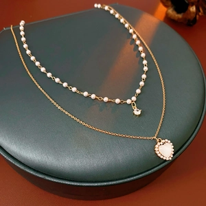Détail d'un collier double rang doré avec perles et pendentif cœur en zircone