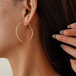 Close-up of a minimalist gold geometric hoop earring worn on a model with metallic shine
