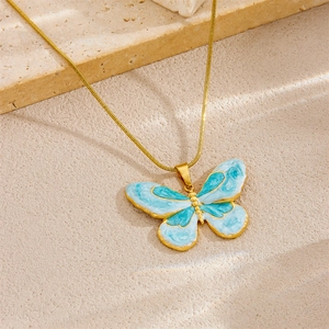 Elegant gold snake chain necklace with blue and white butterfly pendant on beige background