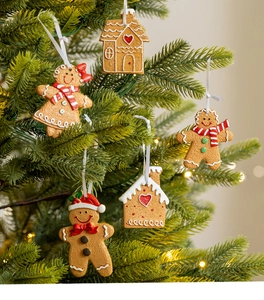 Macro shot of gingerbread man and house ornaments hanging on a green Christmas tree