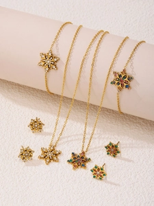 Golden snowflake jewelry set with cubic zirconia stones displayed on beige pedestals