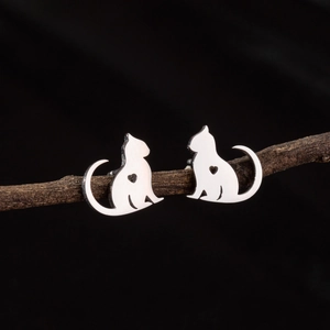 Cute minimalist silver cat earrings with hollow heart detail displayed on a wood branch