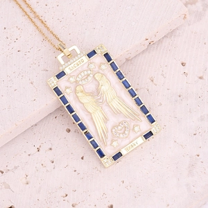 Macro shot of sacred heart pendant with pink enamel and blue crystals on stone