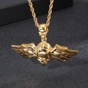Détail d'un collier gothique doré avec un crâne et des ailes d'ange sur fond sombre