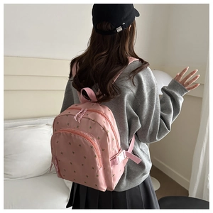 Close-up of pink backpack with floral embroidery and adjustable buckles for students