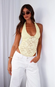 Close-up of yellow lace halter bodysuit styled with white wide-leg denim jeans
