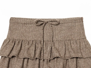 Dettaglio gonna in tweed marrone spina di pesce con fiocco e balze a strati