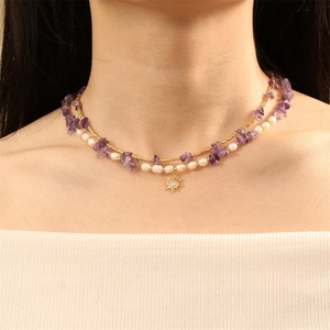 Double-layered necklace with purple gravel, white pearls, and a gold sun pendant on neck
